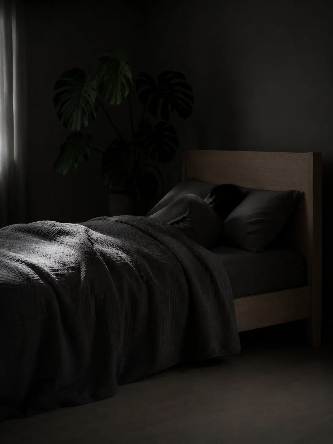 An adult asleep in a dark, calm bedroom